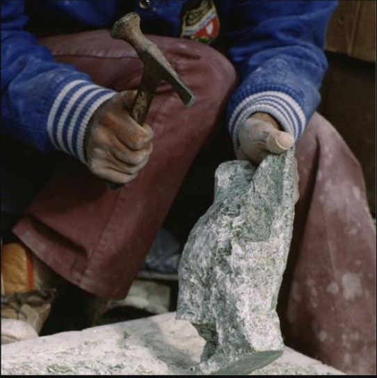 Close-up of hands using a hammer and chisel to cut a stone