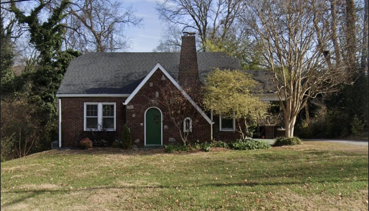 A brick 1920s bungalow home surrounded by bare winter trees