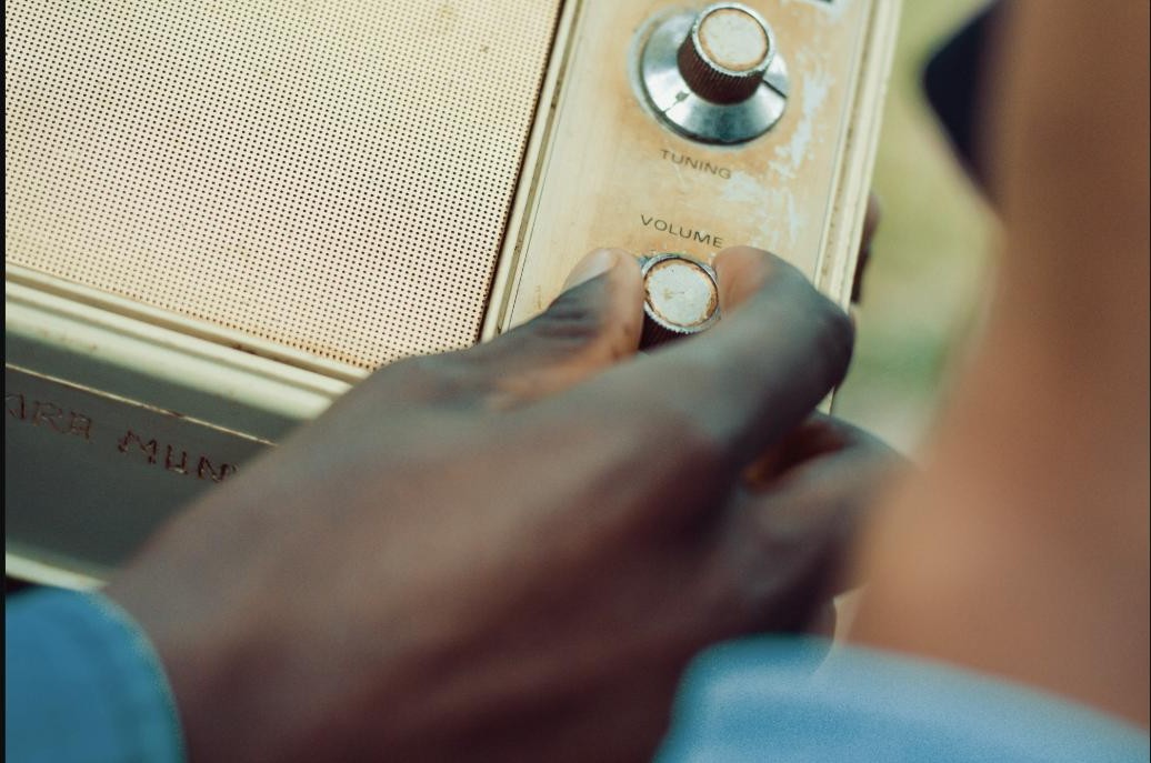 A hand adjusting the volume knob on a vintage radio