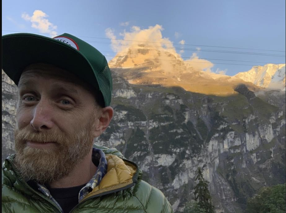 Parker taking a selfie in front of a snow-capped mountain peak in the Swiss Alps